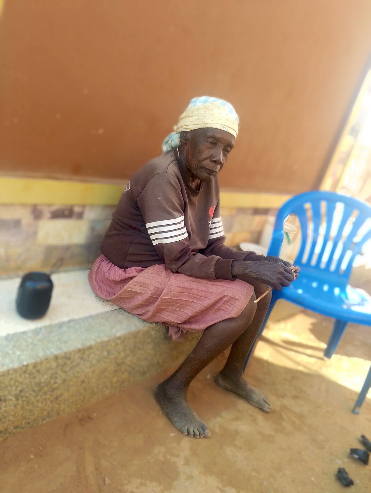Femme âgée assise devant sa maison